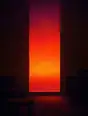 Grainy gradient illustration: A tall window filled edge to edge with dense sunset color, the room around it already dark in flat planes.