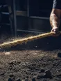 Motion photograph: a heavy rope hauled hand over hand at midday, the line jumping under the load and dust snapping off it