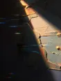 Prism-light photograph: Old paint layers showing where new paint has been scraped back, hard sun raking across the ridges.