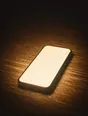 Struck-light photograph: a phone lying face up on a dark desk at night, its screen lit and blank, nothing else on the surface