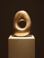 Struck-light photograph: one finished piece on a plinth under a single tight light in an otherwise black room