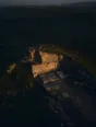 Dawn aerial photograph: a small quarry face glowing in first light, cut stone blocks stacked at its base.
