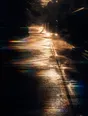 Prism-light photograph: Rain steaming off hot ground down a whole street with hard sun breaking through.