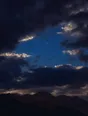 Film photograph: one bright star holding steady in a gap of indigo sky while silver-edged clouds stream past.