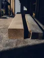 Dark cinematic photograph: A freshly cut length of timber lying next to the mis-cut one it replaces.