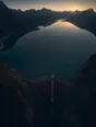 Dawn aerial photograph: a great curved stone dam holding a vast still reservoir at sunrise.