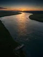 Dawn aerial photograph: a broad river running brim-full at dawn, a small stone quay on its bank.