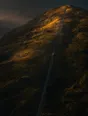 Dawn aerial photograph: a hillside funicular car caught mid-climb, rails running up through long dawn shadows toward the summit light.