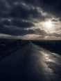 Dark cinematic photograph: A long road running out across open country under a huge sky clearing after rain.