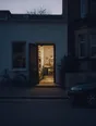 Dark cinematic photograph: A home studio lit from inside, seen from the road at dusk with its door standing open.
