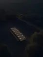 Dawn aerial photograph: a long trestle table set for a dozen in a stone courtyard at first light, still empty.