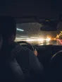 Motion photograph: a man driving home at night in heavy rain, the road and the oncoming lights running past the glass