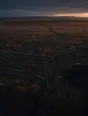 Dawn aerial photograph: a chain and padlock hanging open on a field gate, dew catching the light.