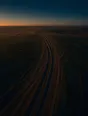 Dawn aerial photograph: fresh wheel tracks running over many older faded ones on a dirt farm lane.