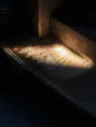 Prism-light photograph: A stone step hollowed by years of feet, hard sun raking across the dish it has worn.