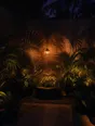 Film photograph: a dark courtyard transformed by one warm hanging lamp, plants throwing dramatic shadows up the walls.