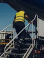 Dark cinematic photograph: One person stepping up onto a platform ladder, seen from behind and below.