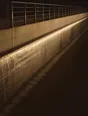 Struck-light photograph: a concrete weir at night, its wall and handrail running away, water going over the crest in a thin line