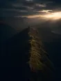 Dawn aerial photograph: a worn path running along a narrow mountain ridgeline toward the light.