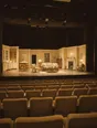 Struck-light photograph: a small theatre at night with the house lights full up and the stage already set