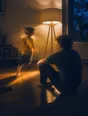 Motion photograph: a man sitting on the floor of a lit front room at dusk while a small child runs laps around him
