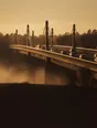 Struck-light photograph: a modern bridge at dawn with mist underneath it and the road across already carrying traffic