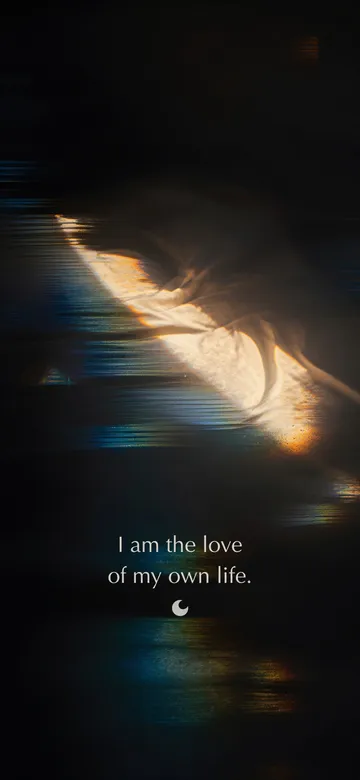 Self-love affirmations wallpaper: prism-light photograph of hard dawn sun striking the crumpled white linen of an unmade bed, the rest of the room fallen to black, with the affirmation 'I am the love of my own life.' in serif type.